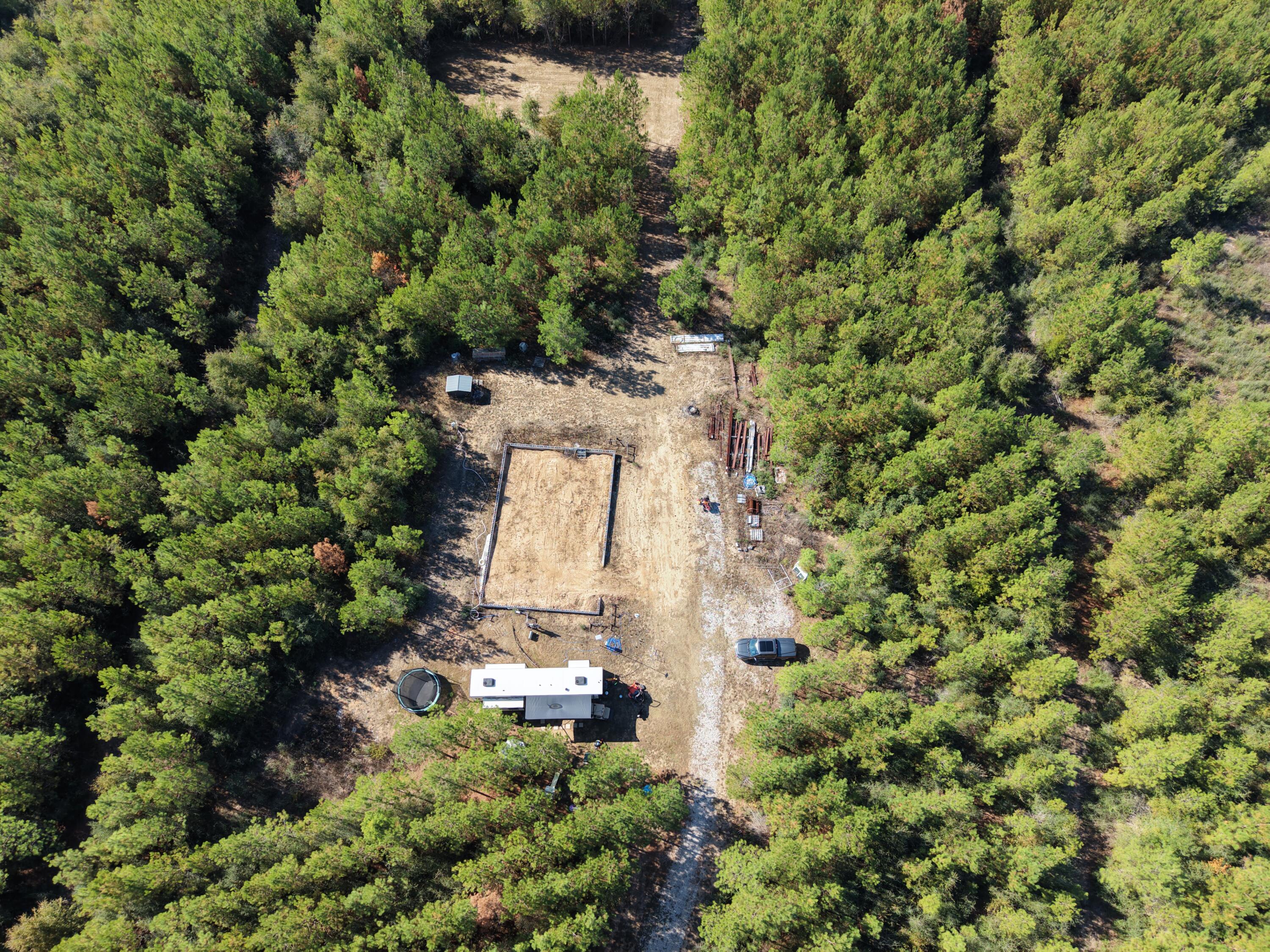an aerial view of residential house with outdoor space and trees all around