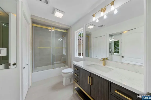 a bathroom with a double vanity sink a toilet a mirror and shower