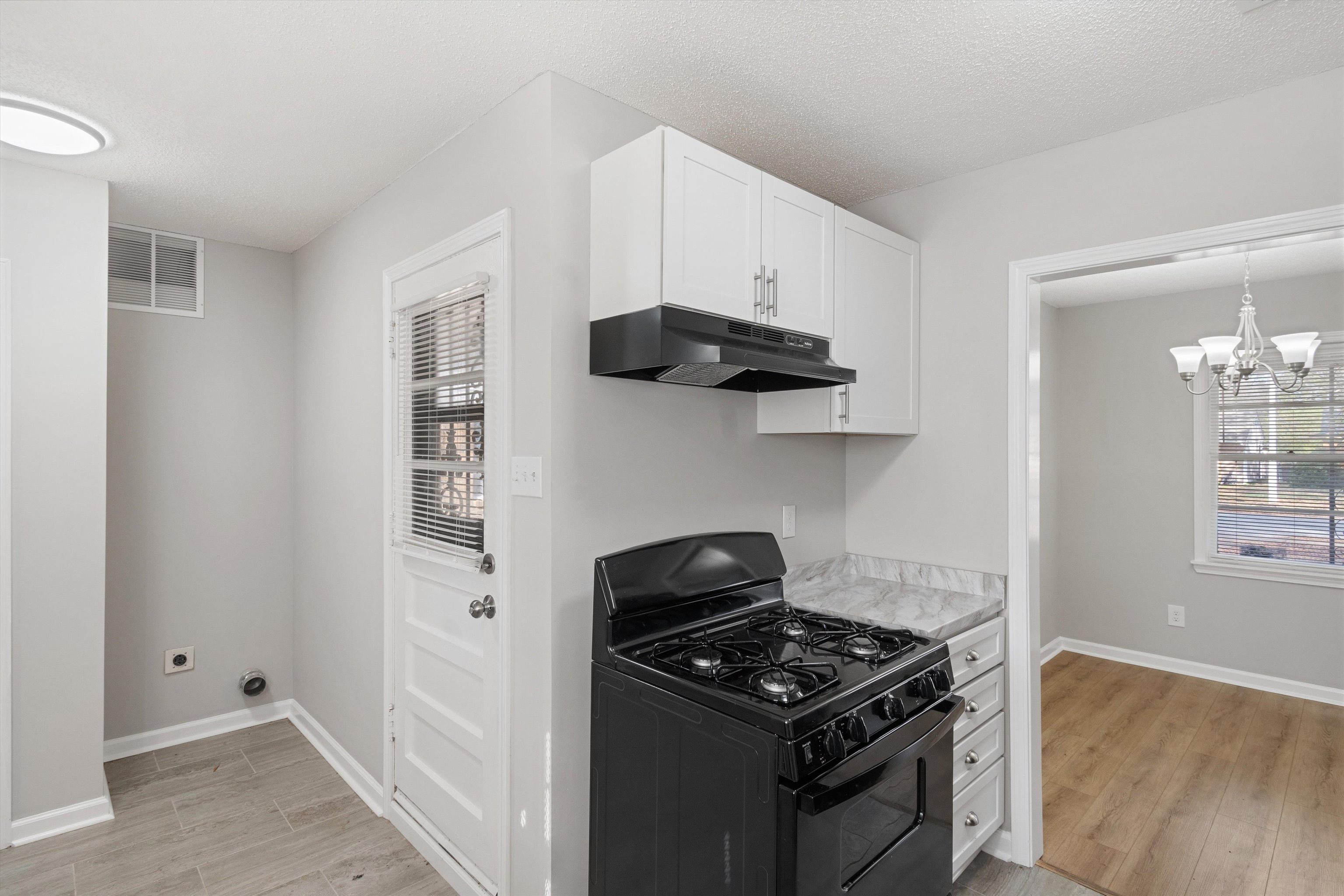 4487 East Dearing Road Memphis, TN 38117 - Photo 10 of 27 Kitchen with black gas range oven, light countertops, white cabinetry, a chandelier, and under cabinet range hood