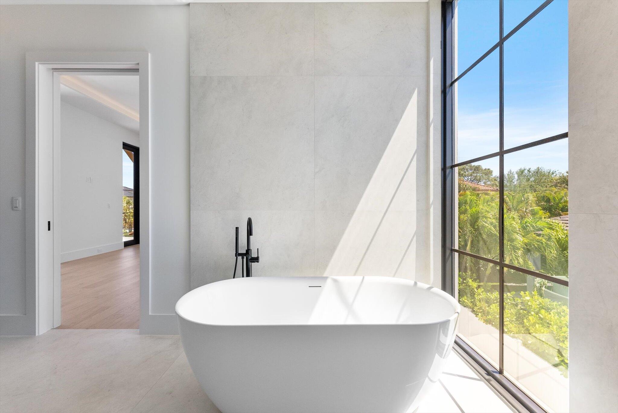 880 Northeast 3rd Avenue Boca Raton, FL 33432 - Photo 50 of 100 a white bath tub sitting in a bathroom next to a window