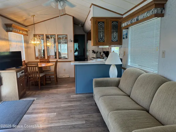 a living room with furniture a flat screen tv and kitchen view