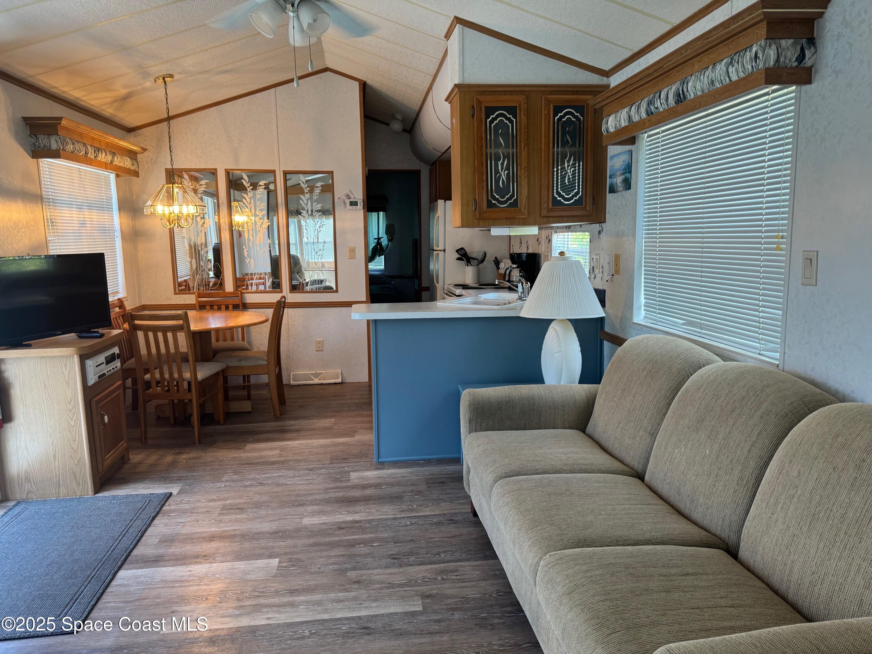 661 Snowbird Avenue, Unit 200 Cocoa, FL 32926 - Photo 3 of 7 a living room with furniture a flat screen tv and kitchen view