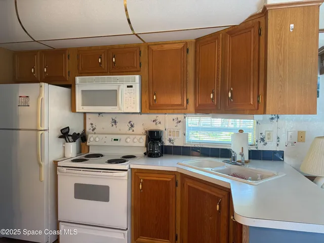 a kitchen with stainless steel appliances a refrigerator a sink a stove and white cabinets