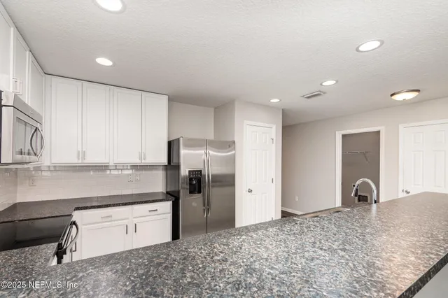 a kitchen with stainless steel appliances granite countertop a refrigerator and a sink