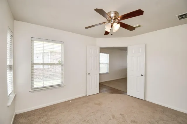 an empty room with windows and fan