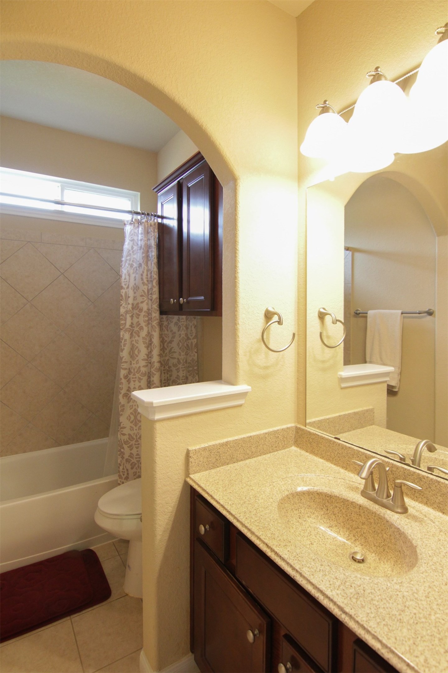 1423 Ralston Branch Way Sugar Land, TX 77479 - Photo 30 of 43 full hall bath with archway between vanity and tiled shower/tub with cabinet above toilet