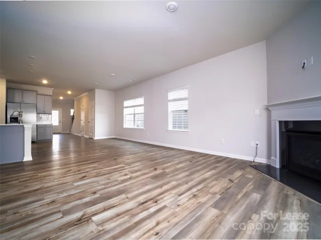 a view of empty room with kitchen and fireplace