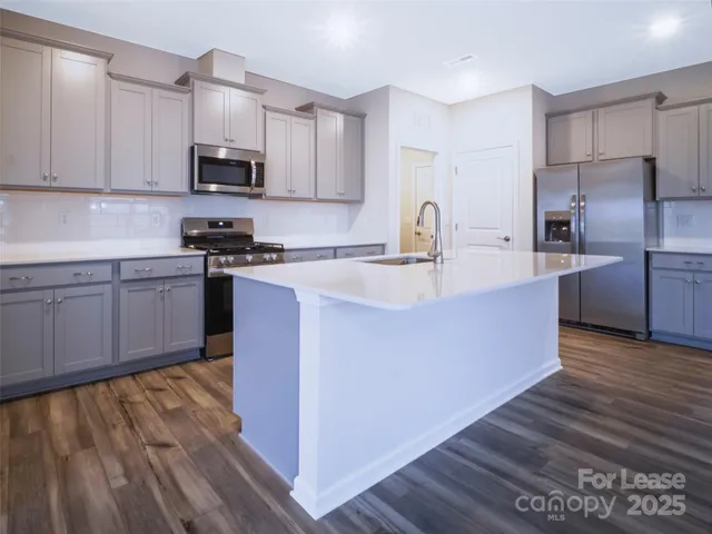 a kitchen with kitchen island granite countertop a sink cabinets and stainless steel appliances
