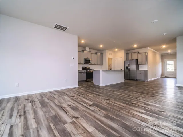 a view of kitchen with kitchen island wooden floor center island and stainless steel appliances