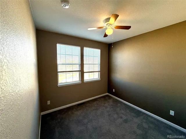 en empty room with windows and chandelier fan