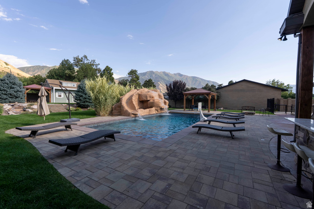687 South 2080th Street East Springville, UT 84663 - Photo 98 of 149 Outdoor entertaining space featuring an integrated swimming pool with a rock slide, a paved patio, and a built-in outdoor bar with stone veneer