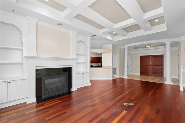 a view of an empty room with wooden floor fireplace and a window