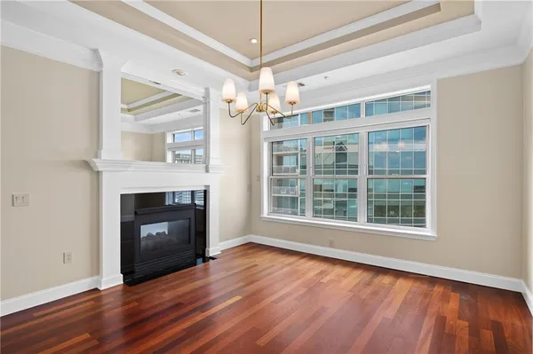 a view of an empty room with wooden floor fireplace and a window