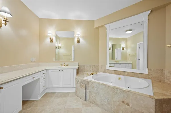 a spacious bathroom with a granite countertop tub sink shower and mirror