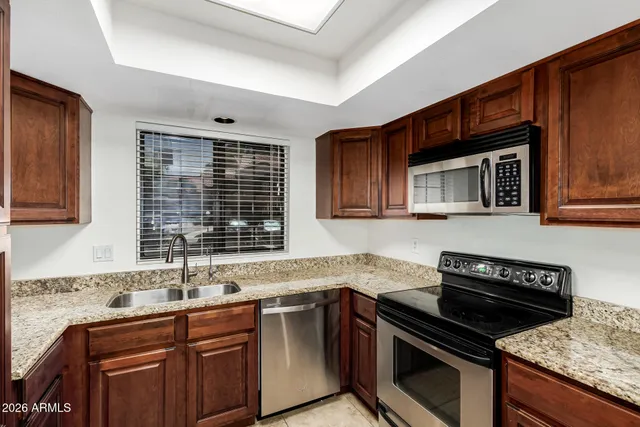 a kitchen with granite countertop a sink cabinets and stainless steel appliances