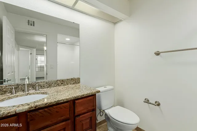 a bathroom with a granite countertop sink a toilet and a mirror