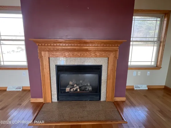 a view of empty room with wooden floor and fireplace