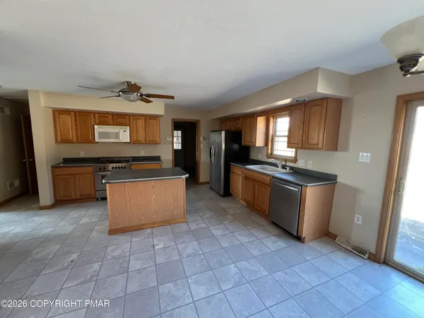 a kitchen with stainless steel appliances kitchen island granite countertop a refrigerator a stove a sink dishwasher and a microwave with wooden floor