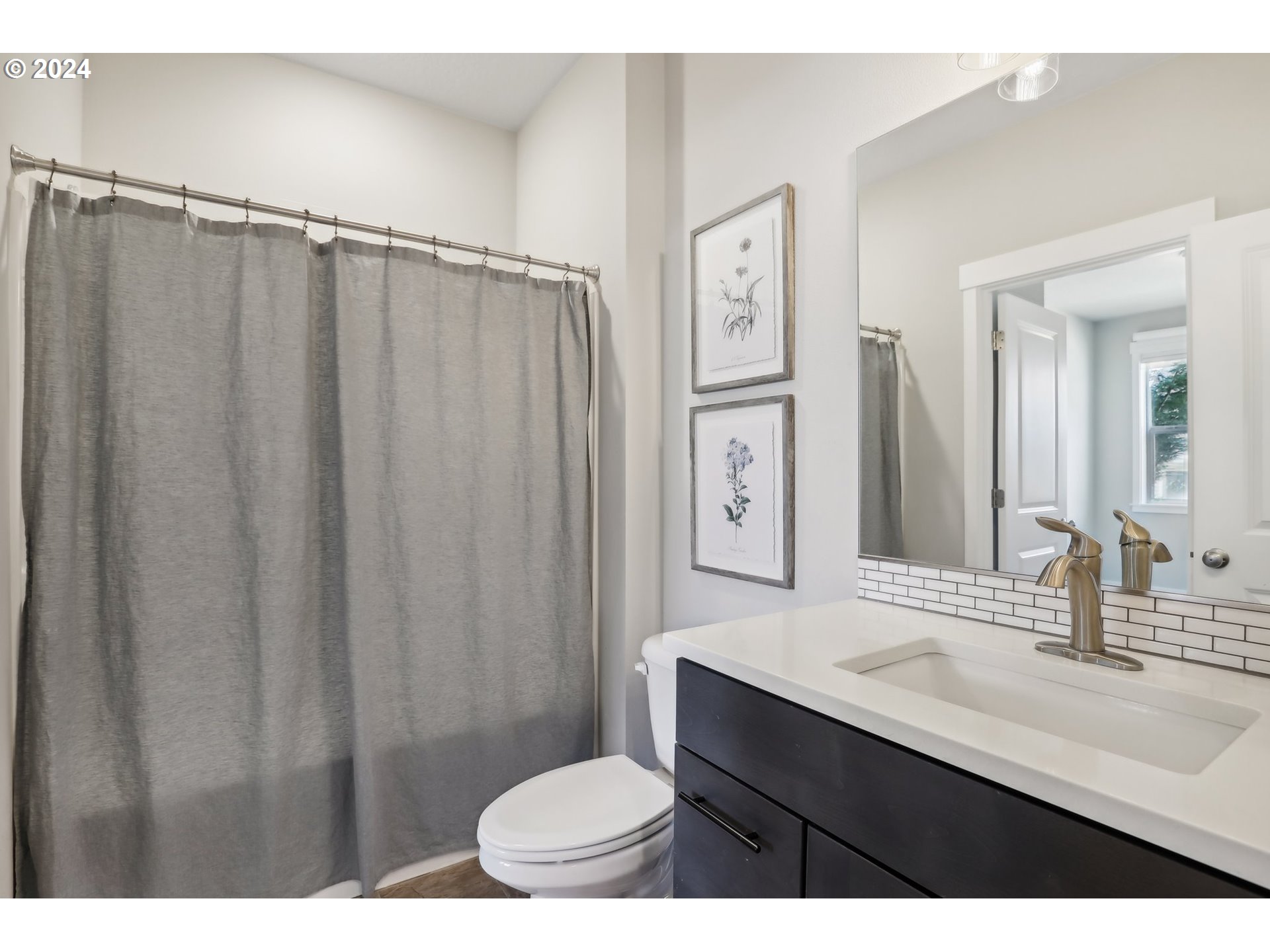 1817 Northeast 171st Street Ridgefield, WA 98642 - Photo 13 of 32 a bathroom with a sink a toilet a mirror and shower curtain