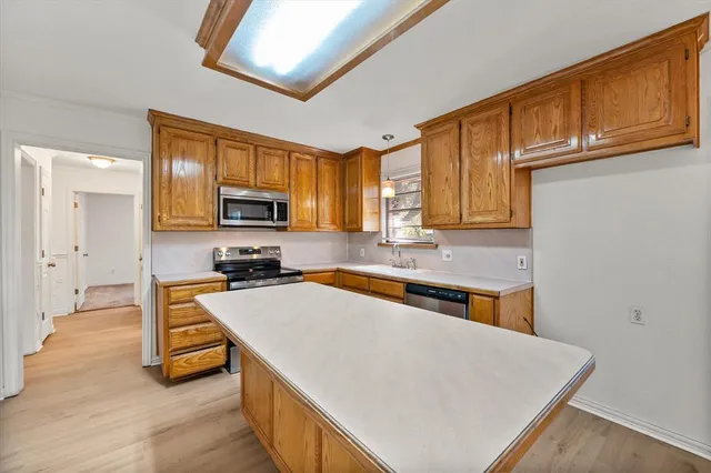a kitchen with stainless steel appliances granite countertop a refrigerator a stove top oven a sink dishwasher and wooden cabinets with wooden floor