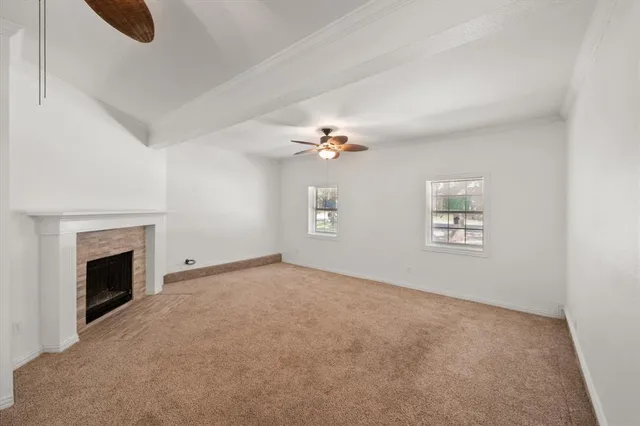 an empty room with chandelier fan and fireplace