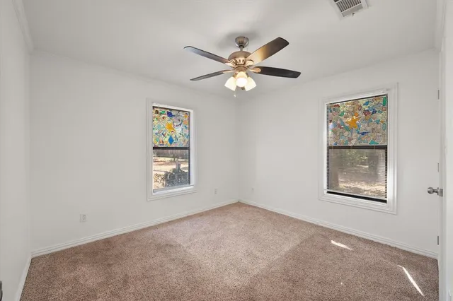 a view of an empty room with a window and a ceiling fan
