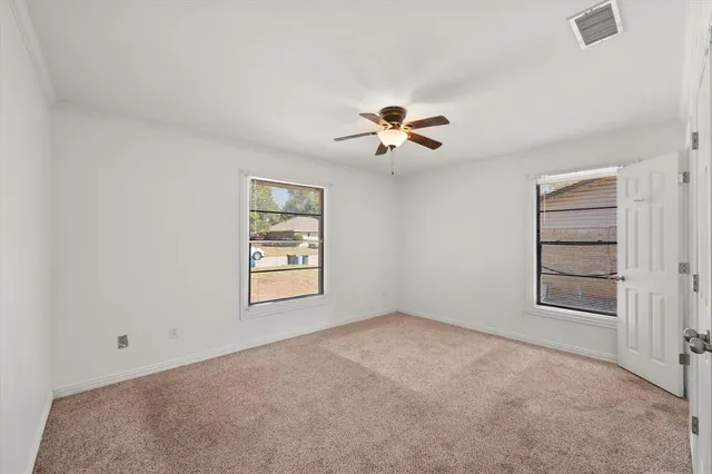 an empty room with windows and chandelier fan