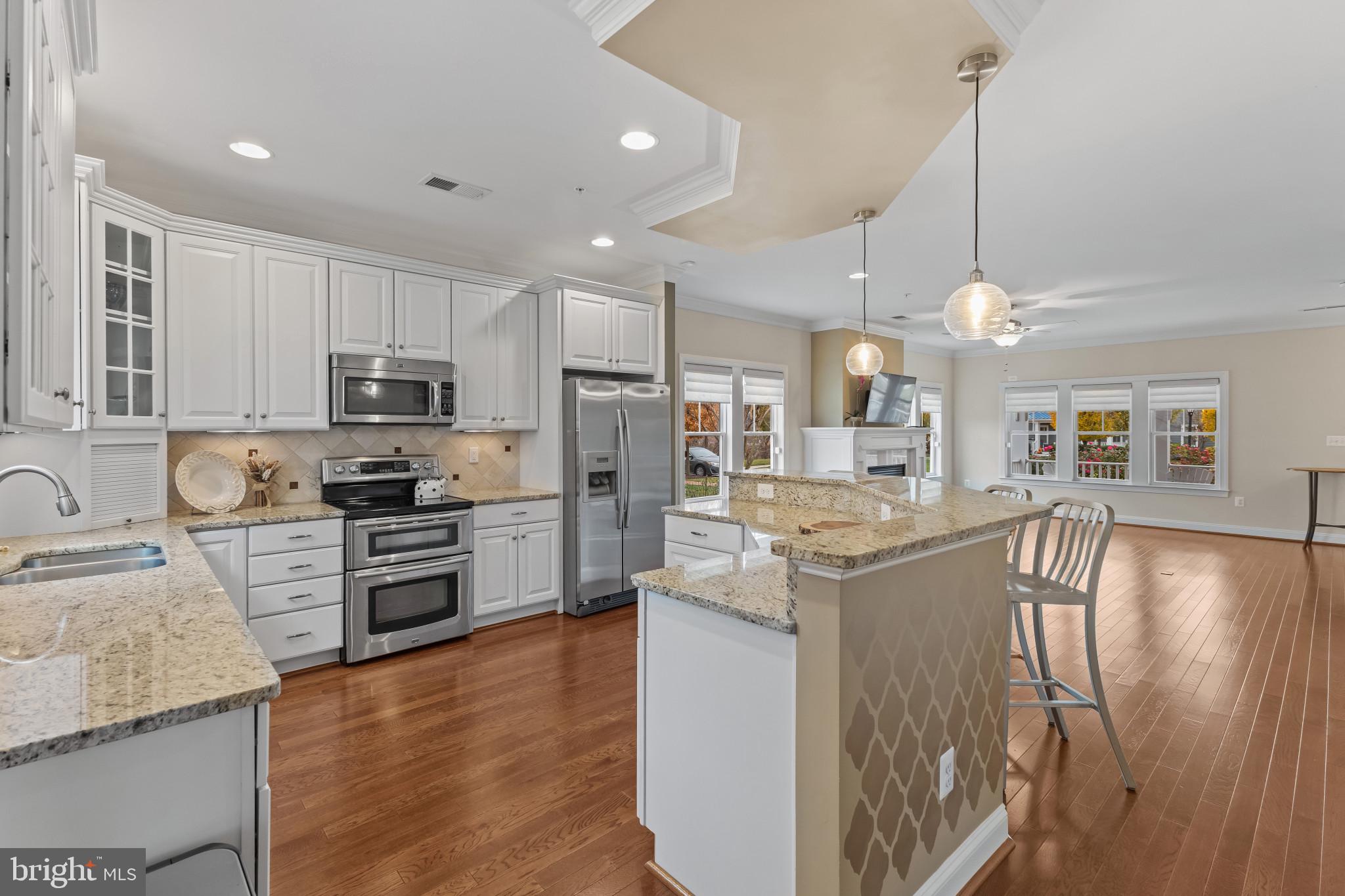132 Claiborne Street Chester, MD 21619 - Photo 9 of 40 a kitchen with kitchen island granite countertop a stove top oven a sink dishwasher a dining table and chairs with wooden floor