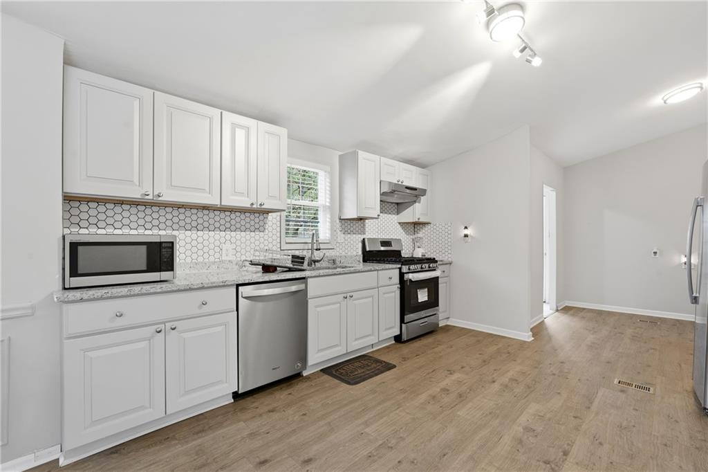 1295 Double Bridges Road Winder, GA 30680 - Photo 8 of 57 a kitchen with granite countertop white cabinets and white appliances