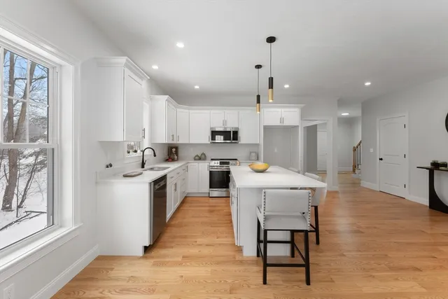 a large white kitchen with lots of counter space wooden floor and appliances