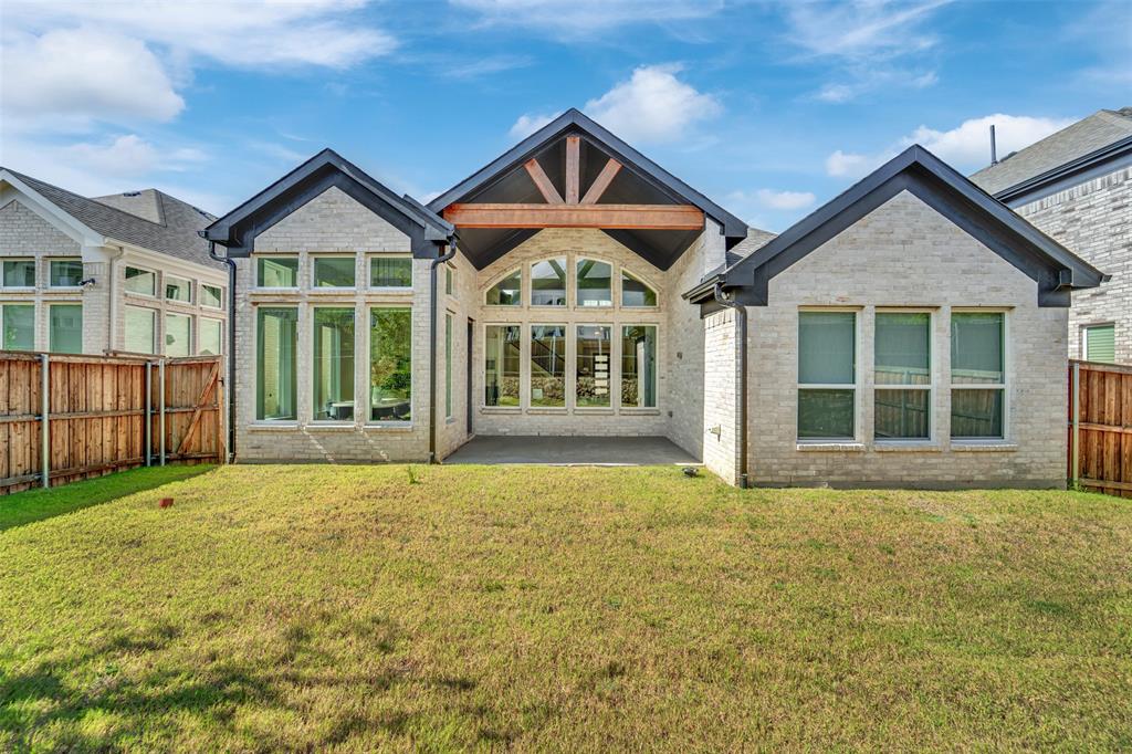 3520 Helios Lane Corinth, TX 76208 - Photo 36 of 37 Rear exterior featuring light-toned brick, dark trim, and a gabled roofline