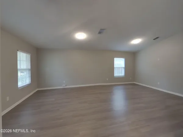 an empty room with wooden floor and windows