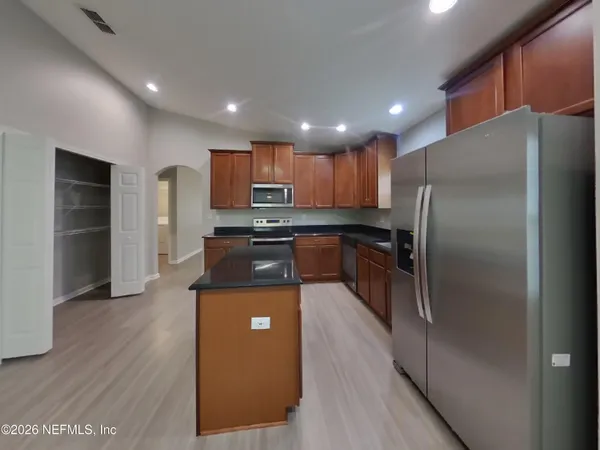 a kitchen with stainless steel appliances granite countertop a refrigerator a stove and a sink with wooden floor