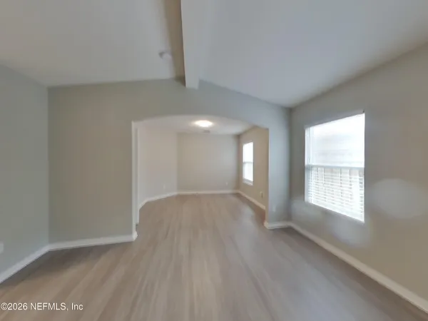 a view of an empty room with wooden floor and window