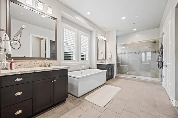 a spacious bathroom with a double vanity sink a large mirror and a bathtub