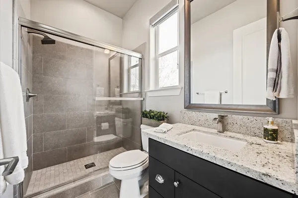 a bathroom with a granite countertop sink toilet and shower