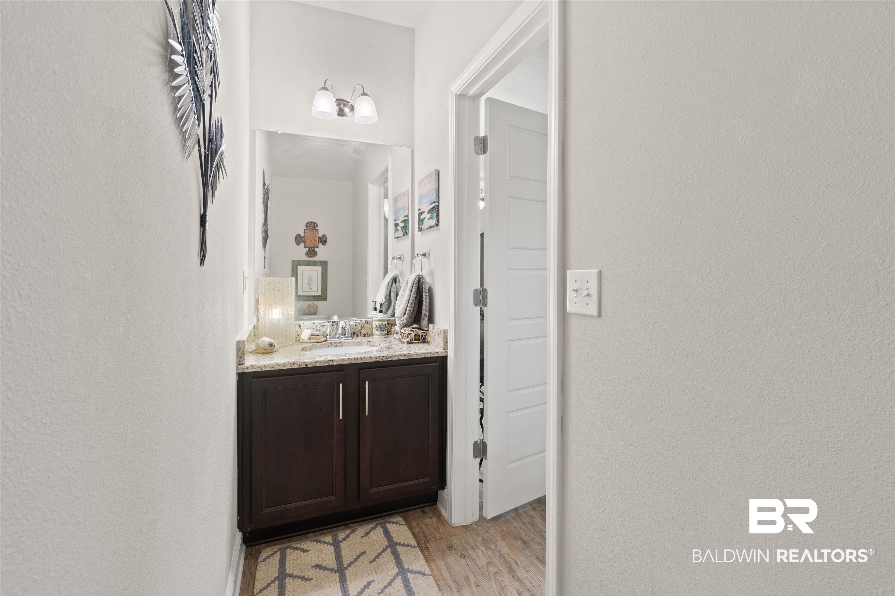 25806 Pollard Road, Unit 6 Daphne, AL 36526 - Photo 11 of 38 Powder room featuring a dark wood-finish vanity with a light-colored granite countertop, an undermount sink, and a large wall-mounted mirror