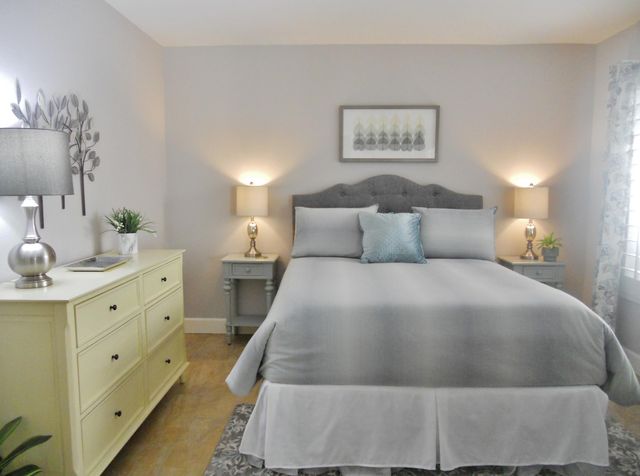 a bedroom with a bed and a lamp on dresser