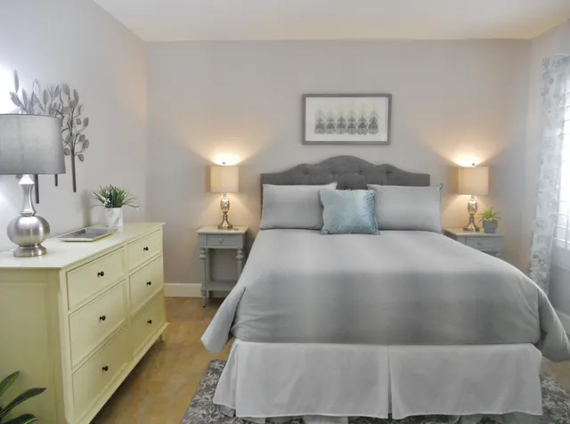 a bedroom with a bed and a lamp on dresser