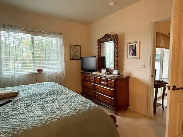 a bedroom with a bed and a flat tv screen on a dresser