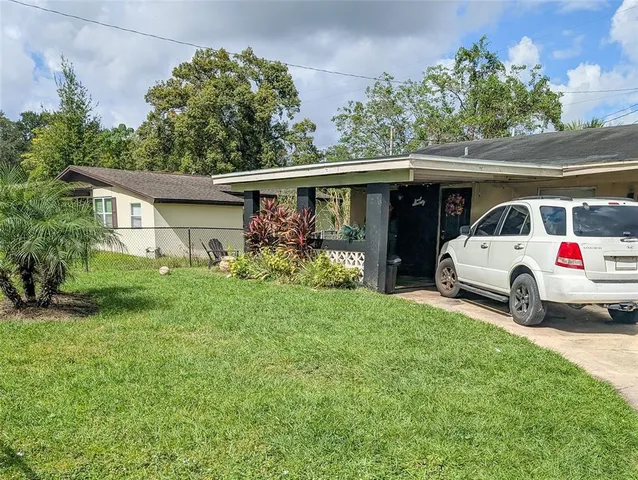 a view of a white house and a yard with a car parked in front of it