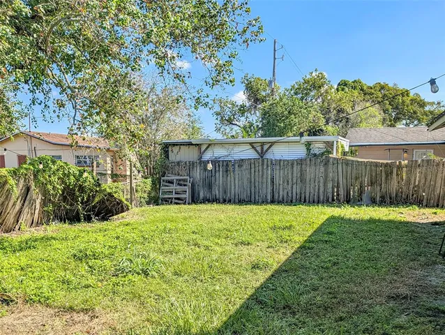 a view of a backyard with wooden fence and trees