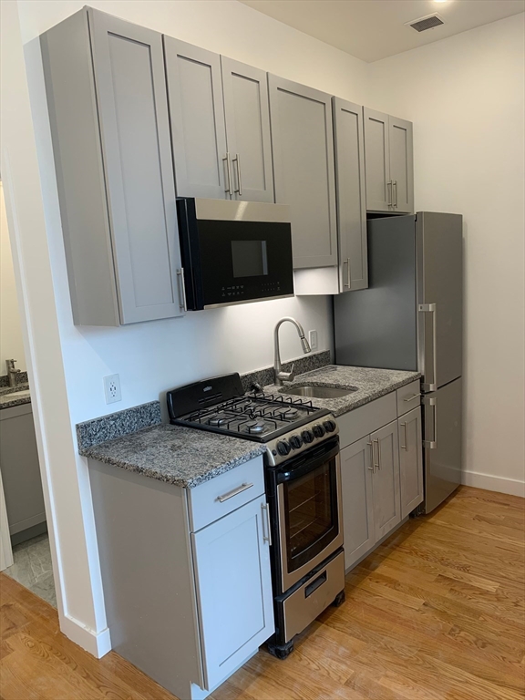 52 Washington Avenue, Unit 403 Chelsea, MA 02150 - Photo 4 of 9 a kitchen with stainless steel appliances granite countertop a stove a refrigerator and a microwave