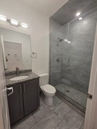 a bathroom with a granite countertop sink a toilet and shower