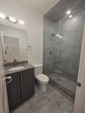 a bathroom with a granite countertop sink a toilet and shower