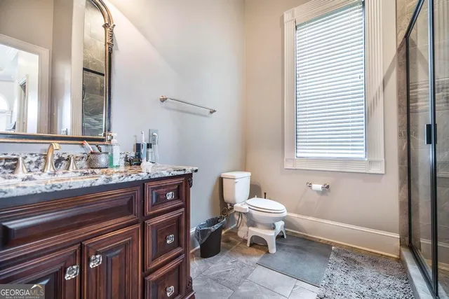 a bathroom with a granite countertop sink a toilet a mirror and shower
