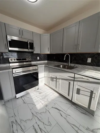 a kitchen with stainless steel appliances granite countertop a sink stove and microwave