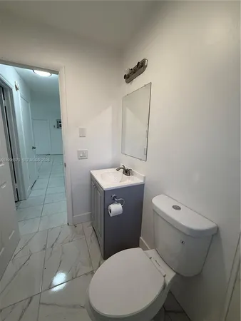 a white toilet sitting next to a bathroom sink and a mirror