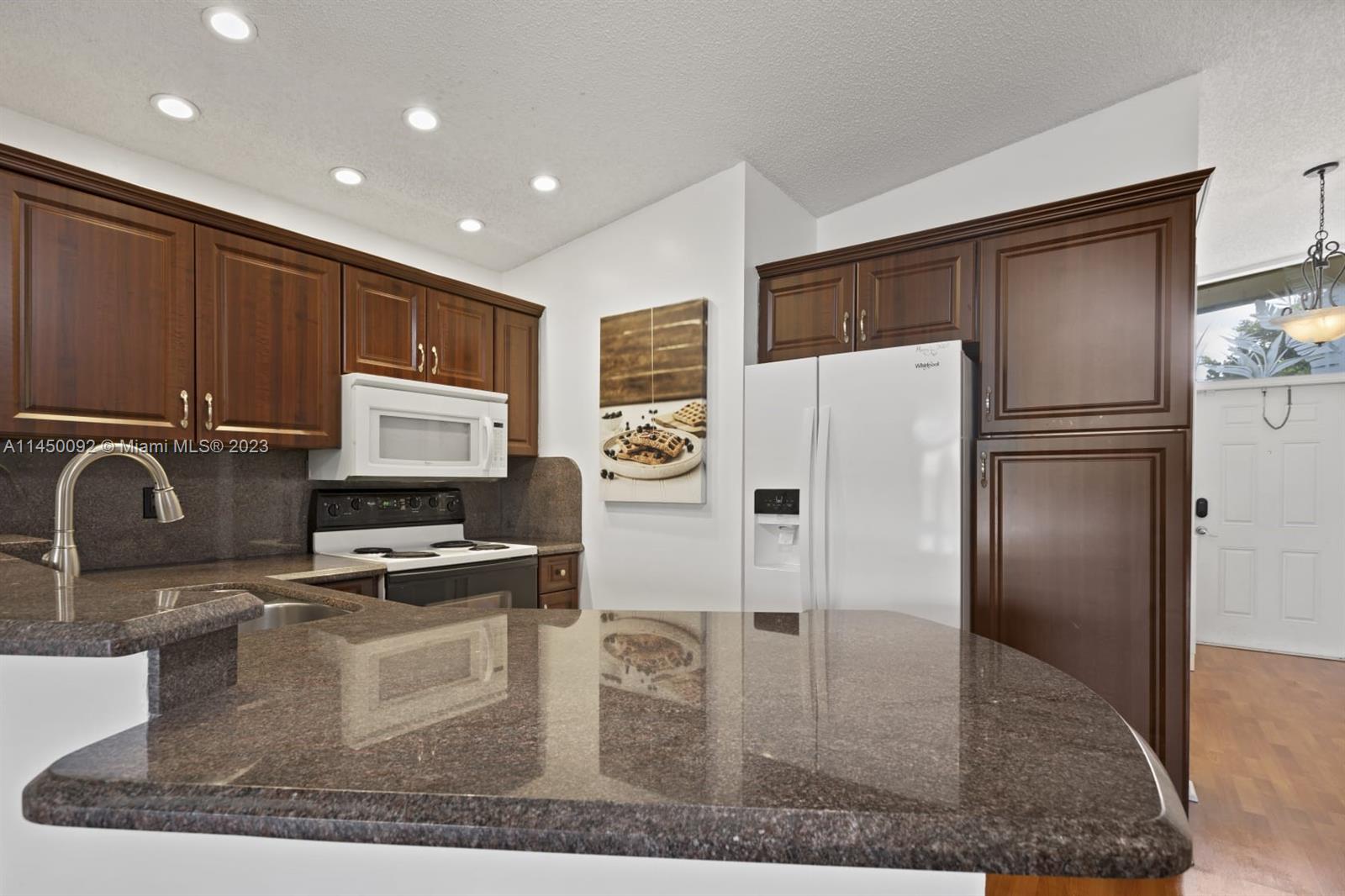 11671 Timbers Way Boca Raton, FL 33428 - Photo 4 of 25 a kitchen with stainless steel appliances granite countertop a refrigerator a stove and a sink with wooden cabinets