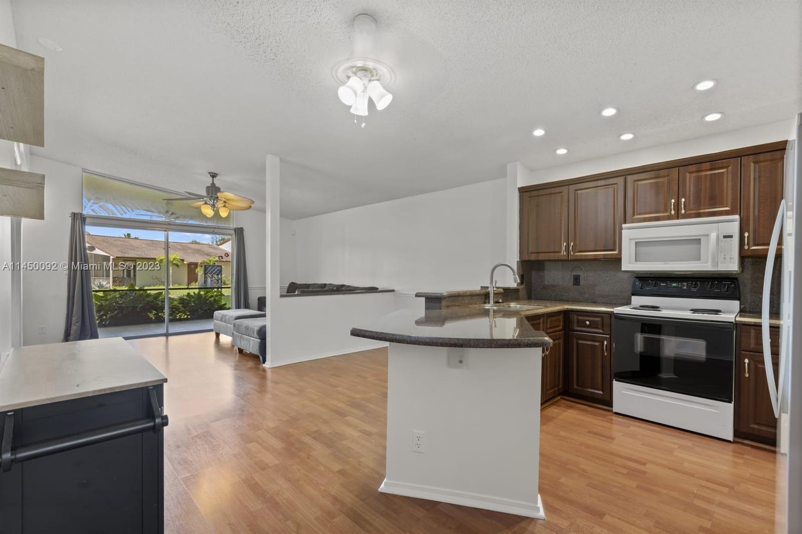 11671 Timbers Way Boca Raton, FL 33428 - Photo 5 of 25 a kitchen with stainless steel appliances granite countertop a sink stove and wooden floor